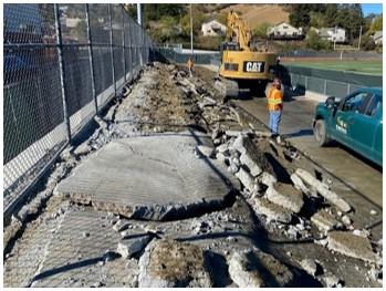 An image of multiple sizes of pieces of concrete as the footings are removed. A tractor is visible in the top right of the image.